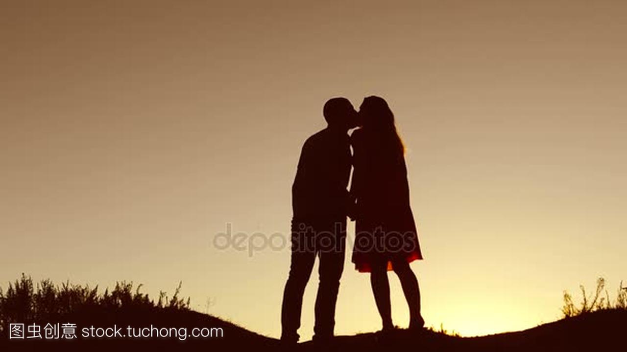 情侣在爱的吻走在剪影自然日落慢动作视频。男