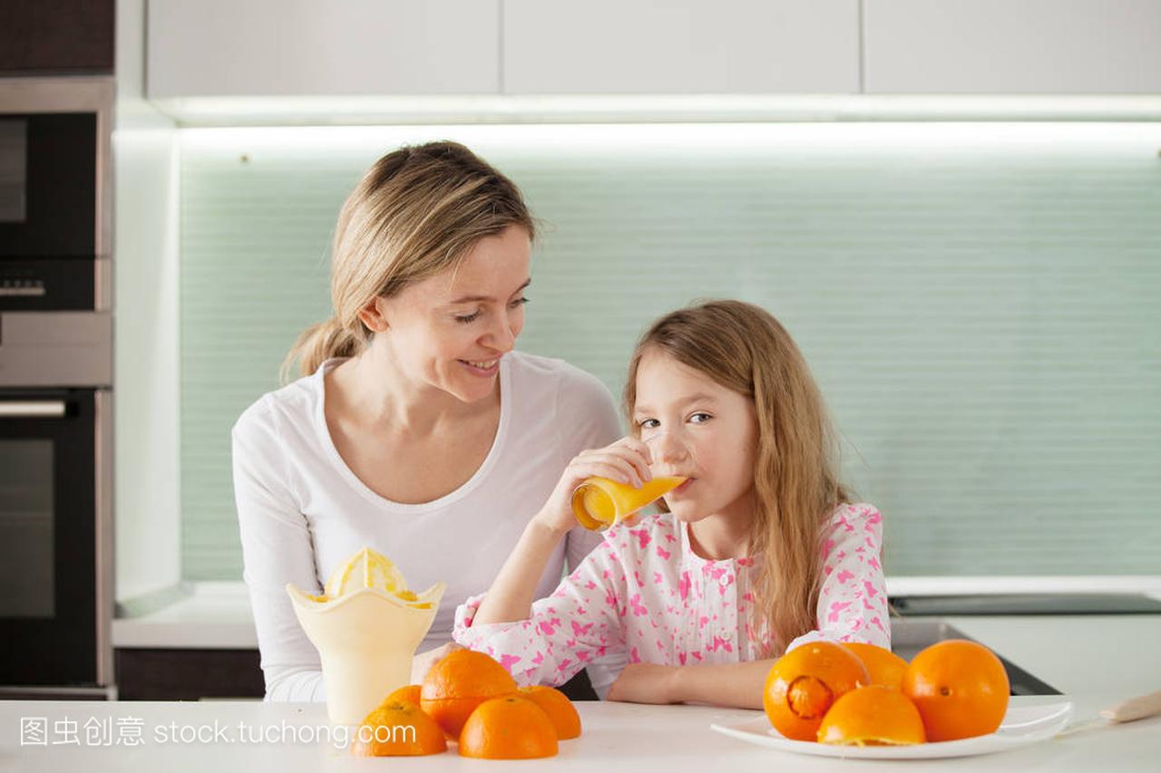 母亲和女儿在榨汁机制作橙汁