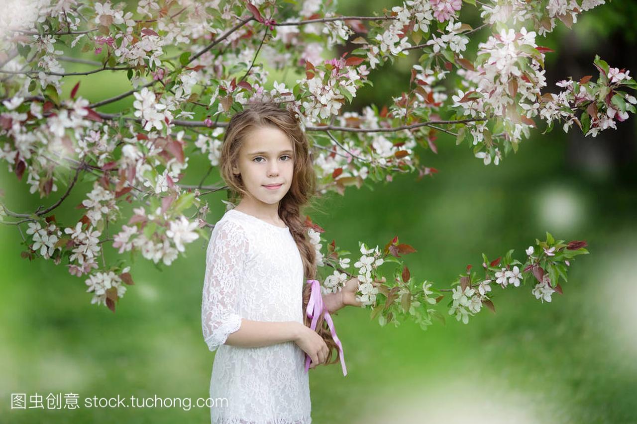 春天肖像在苹果花年轻漂亮长发穿白裙子的女孩