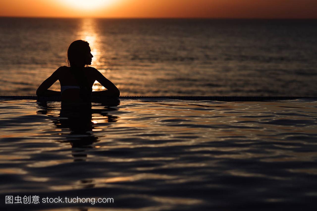 一个女孩在游泳池,在海中翻滚的剪影
