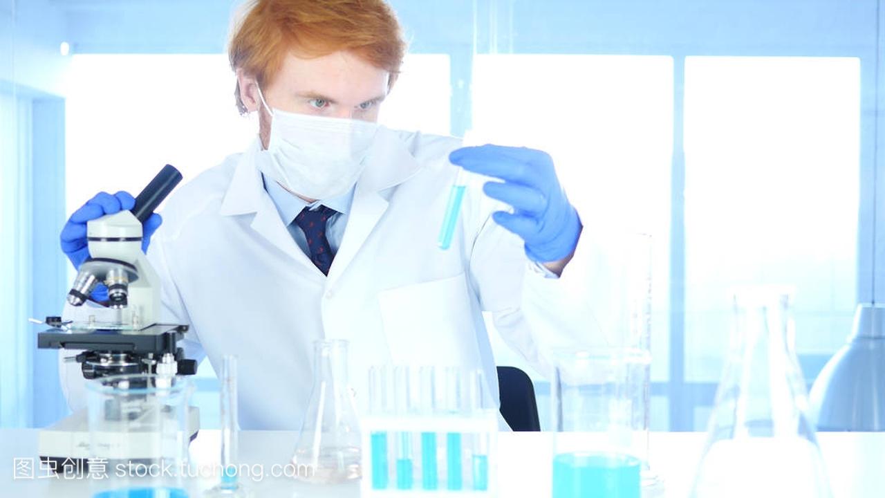 科学家看着试管蓝色解决方案和在实验室中使用