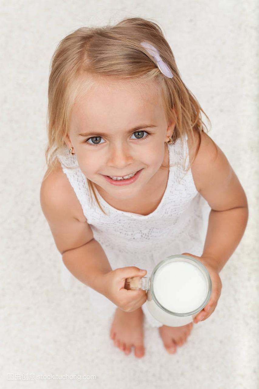 小小快乐的女孩拿着一杯牛奶-顶视图