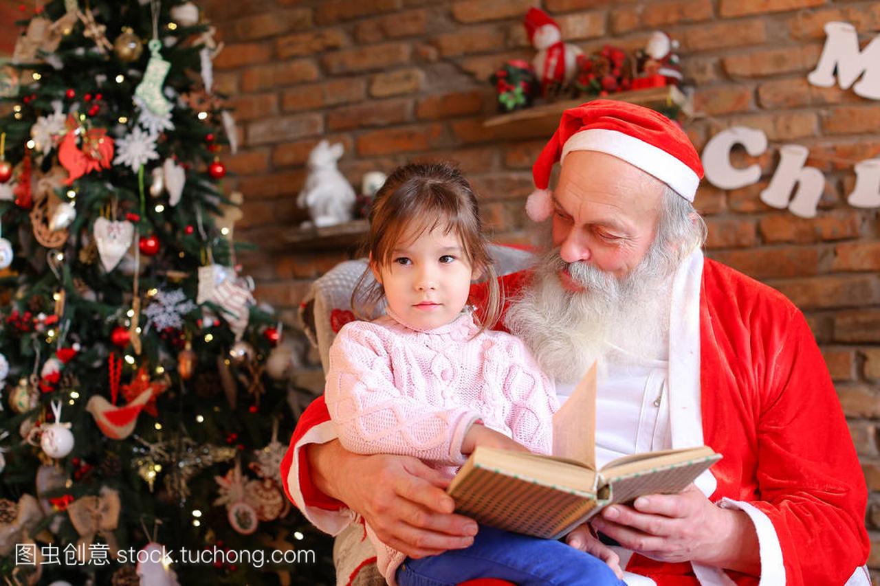 圣诞老人坐在扶手椅上, 读着一本童话故事