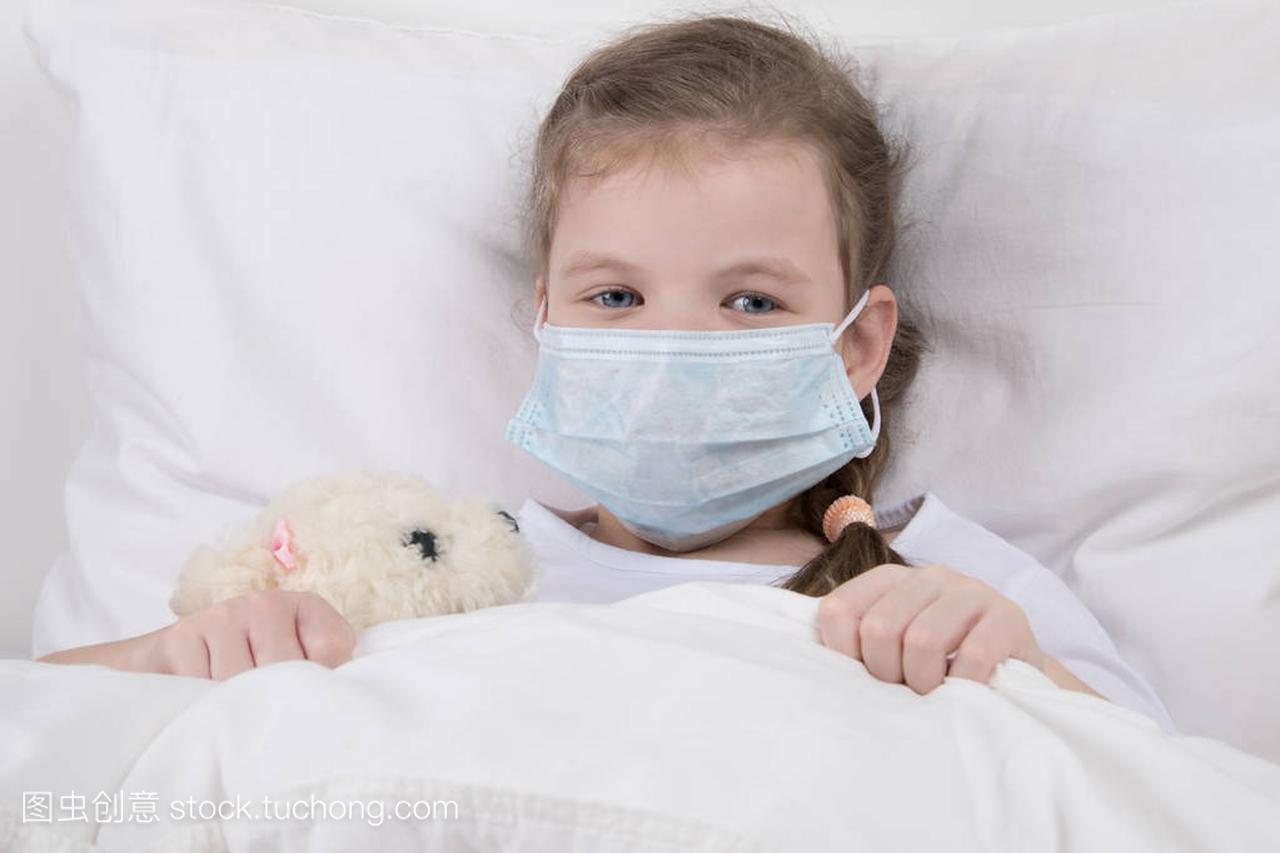 孩子在白床上, 脸上戴着医用口罩, 抵御流感