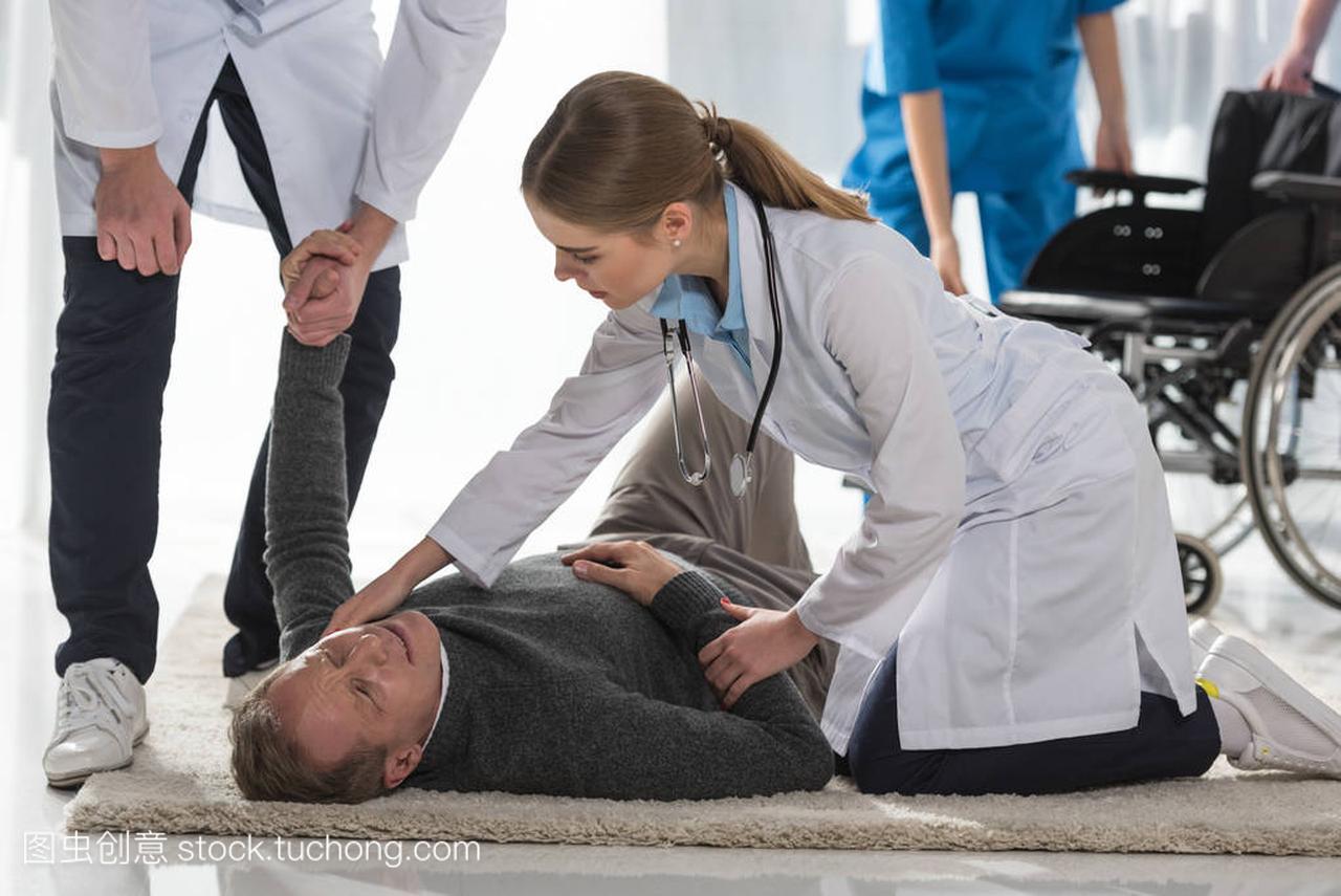 医生的裁剪图象检查成熟的人的脉搏躺在地板上