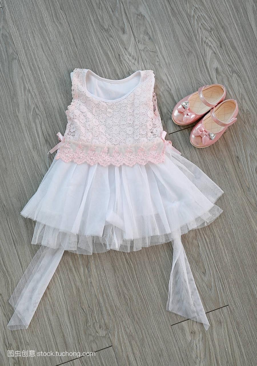 粉红色白色蕾丝连衣裙与女孩的小鞋子在木背景