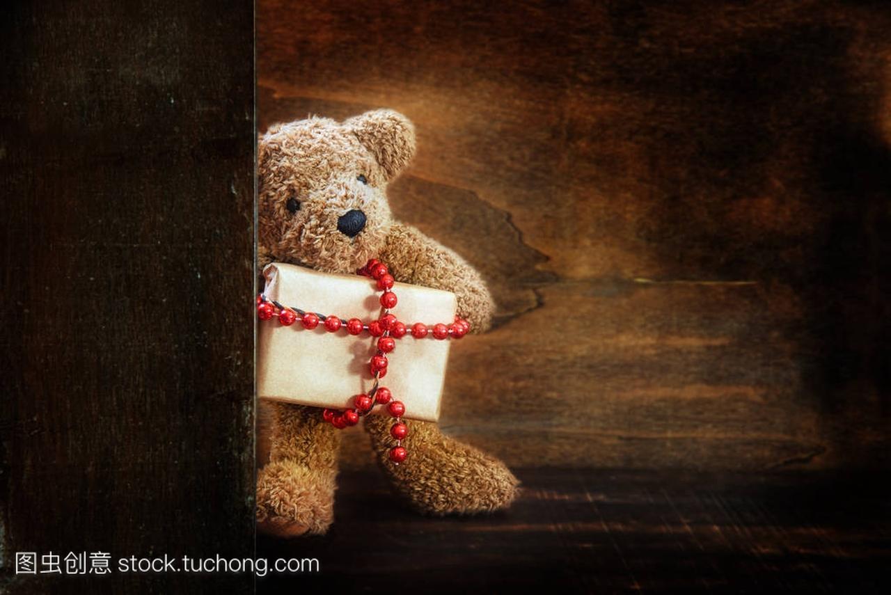 可爱的小泰迪熊一半背后的木墙带来了圣诞礼物