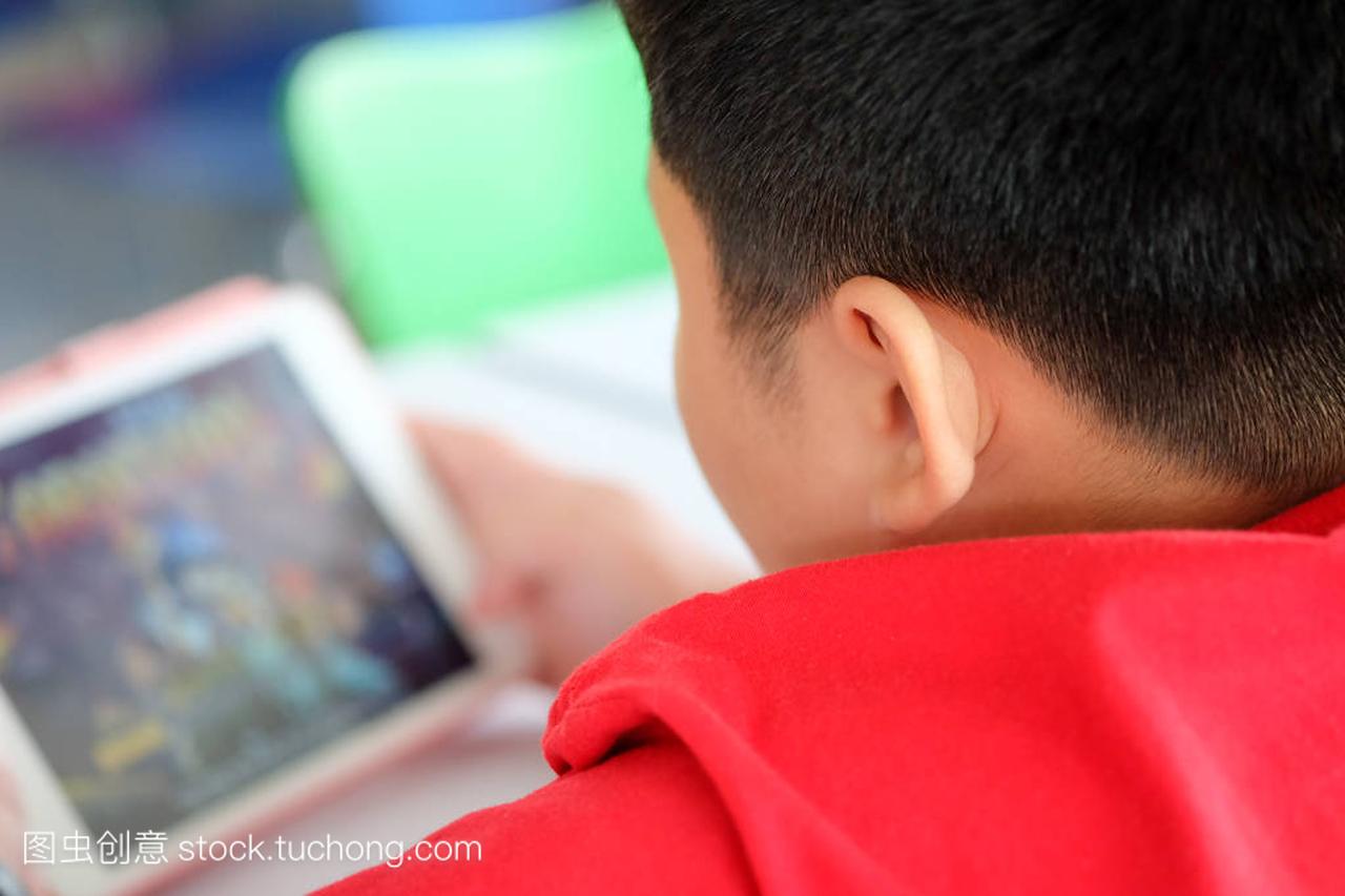 亚洲儿童男孩沉迷于玩平板电脑和手机, 游戏成
