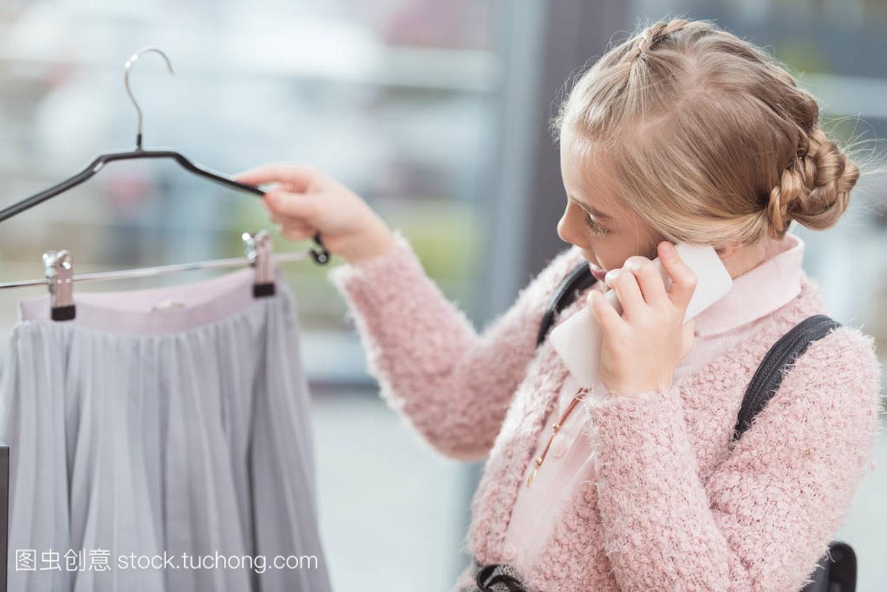 孩子说话的智能手机, 同时拿着衣架在商店的手