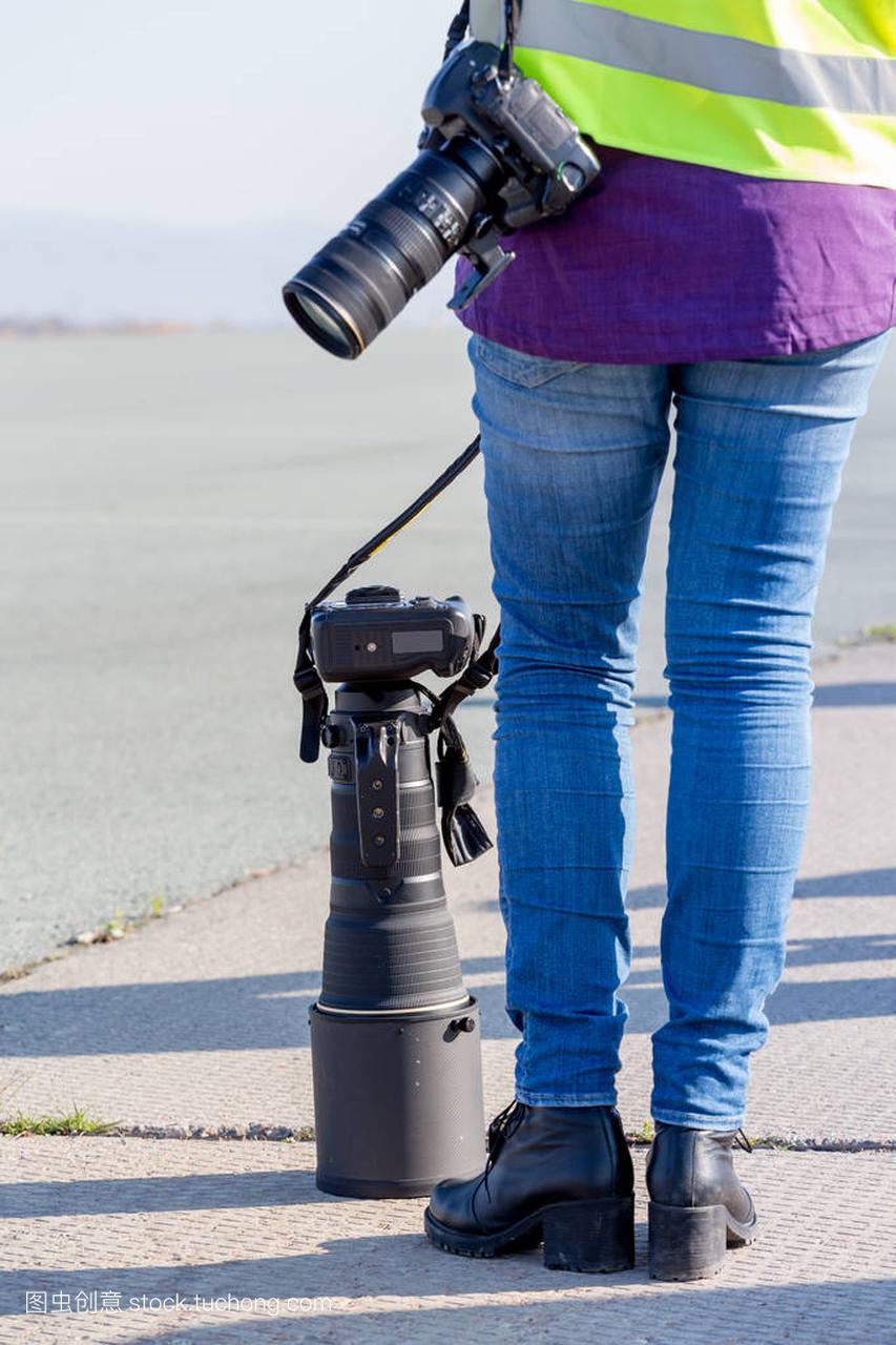 摄影师与现代数码相机和大型长焦镜头站在户外
