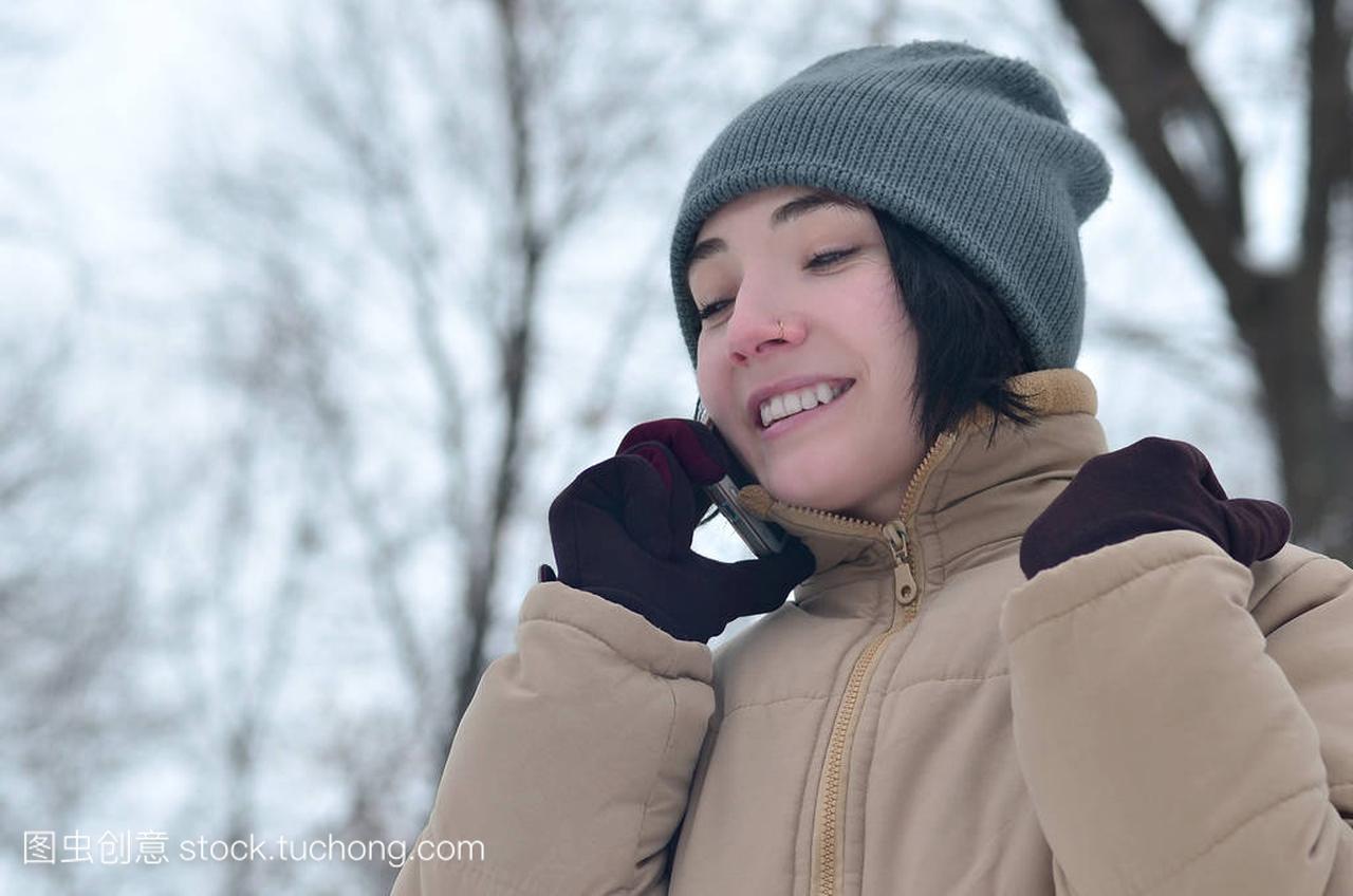 年轻漂亮的女孩穿温暖的冬天帽子和外套。智能