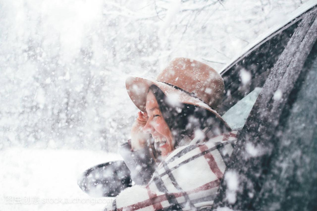 快乐的女人戴着帽子和格子围巾挂在窗外, 在冬