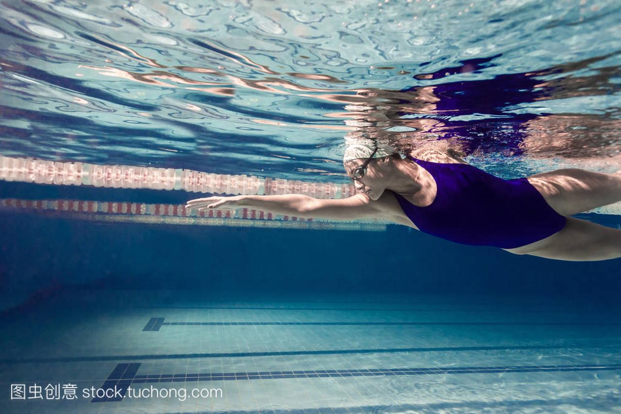 年轻女子游泳运动员在泳池中运动的水下图片