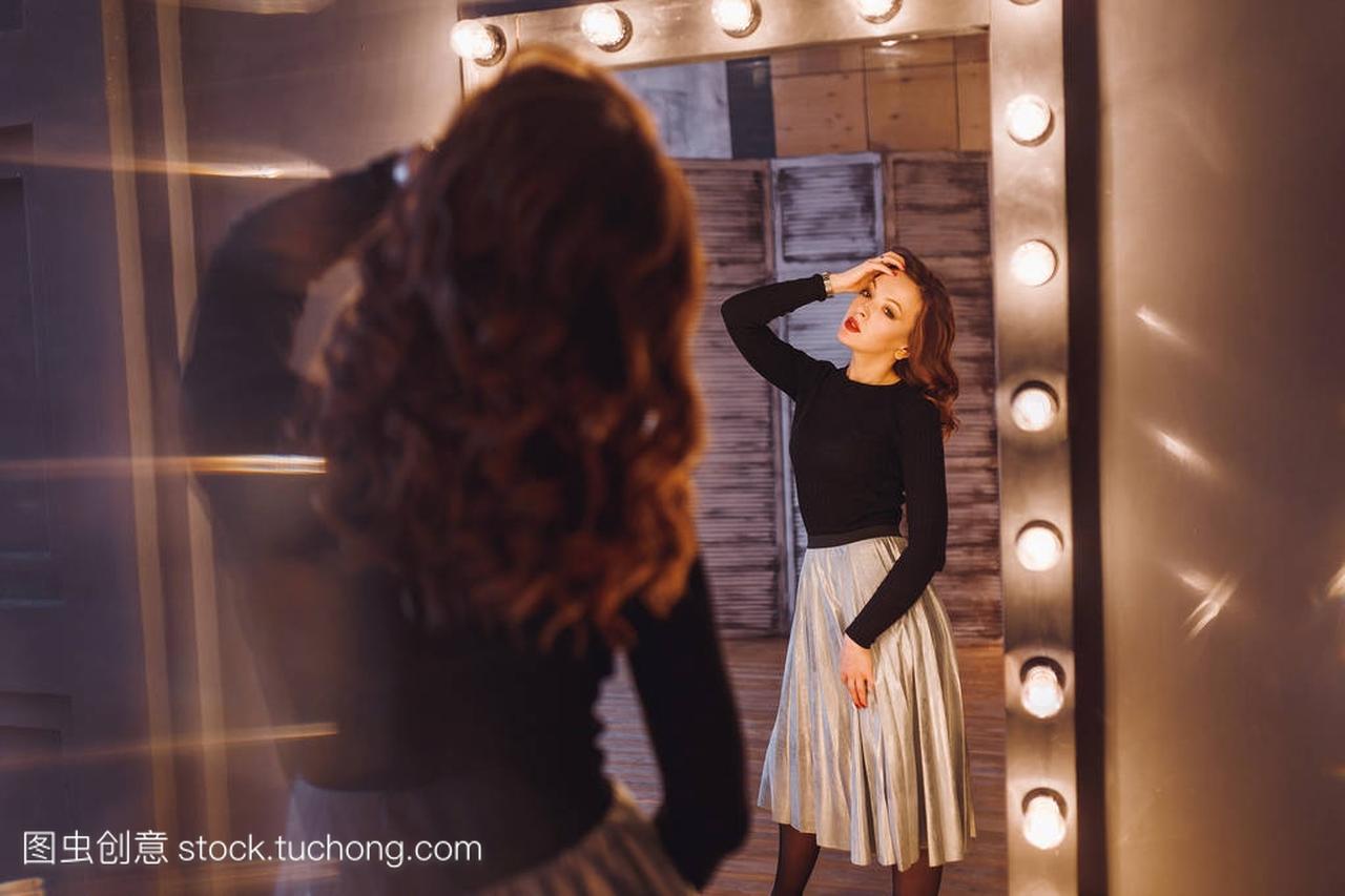 在一家美容院的女人用灯看着镜子里的自己的映