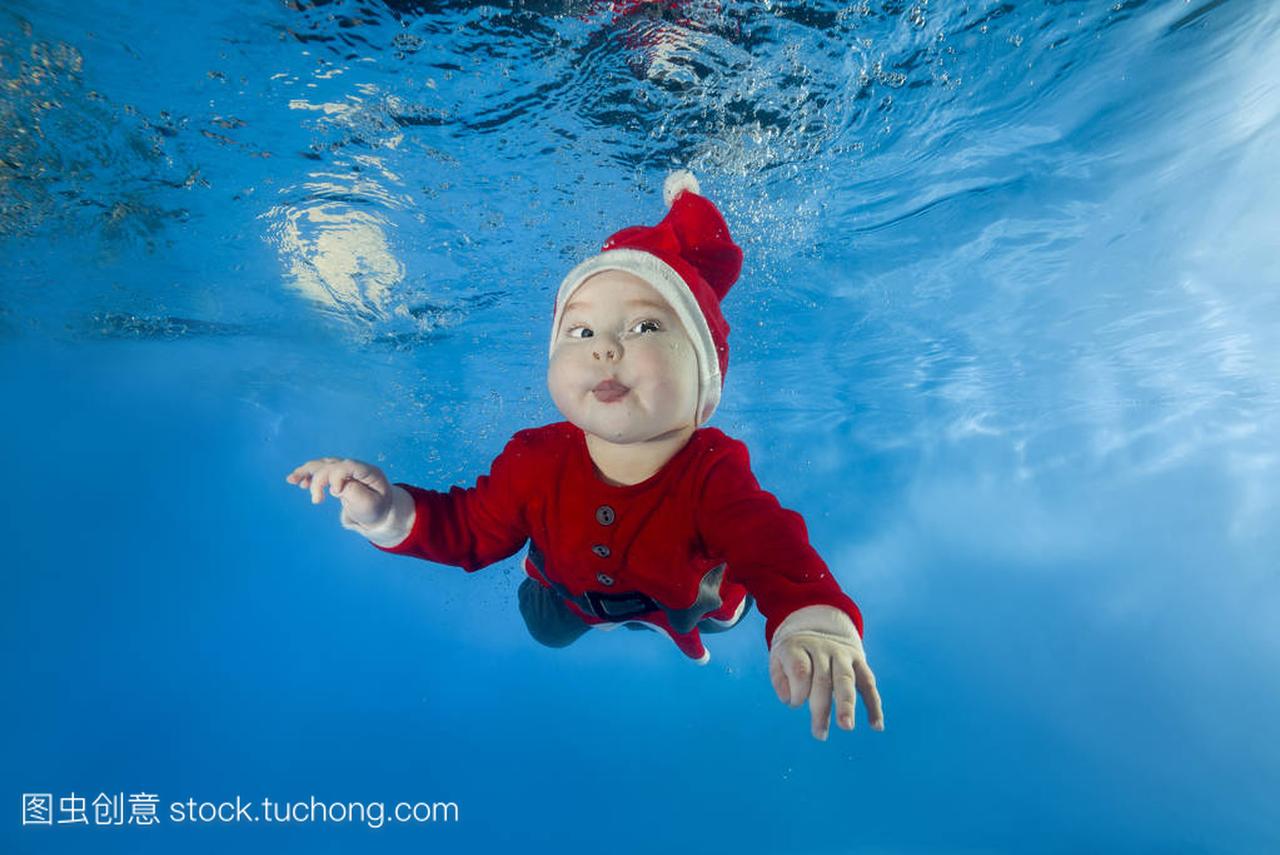一个小男孩在圣诞老人的成本游泳水在水池