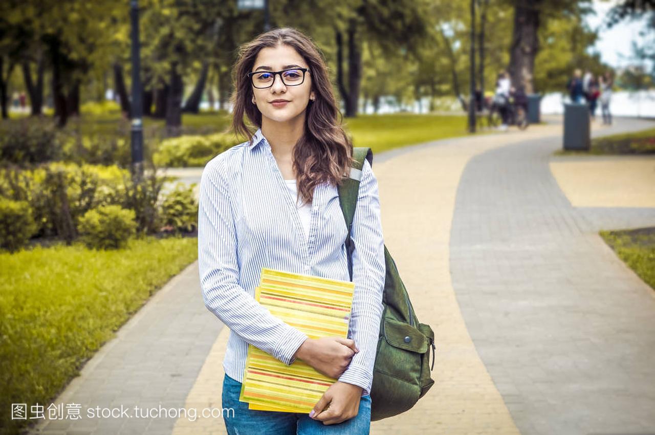 一个女孩, 一个戴眼镜的学生, 在公园里看书。