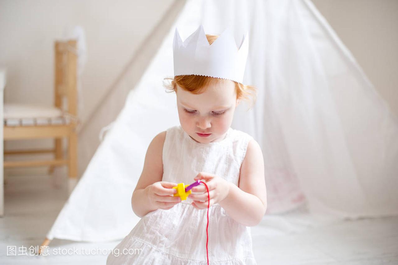 三岁的女孩在皇冠上玩一个教育玩具