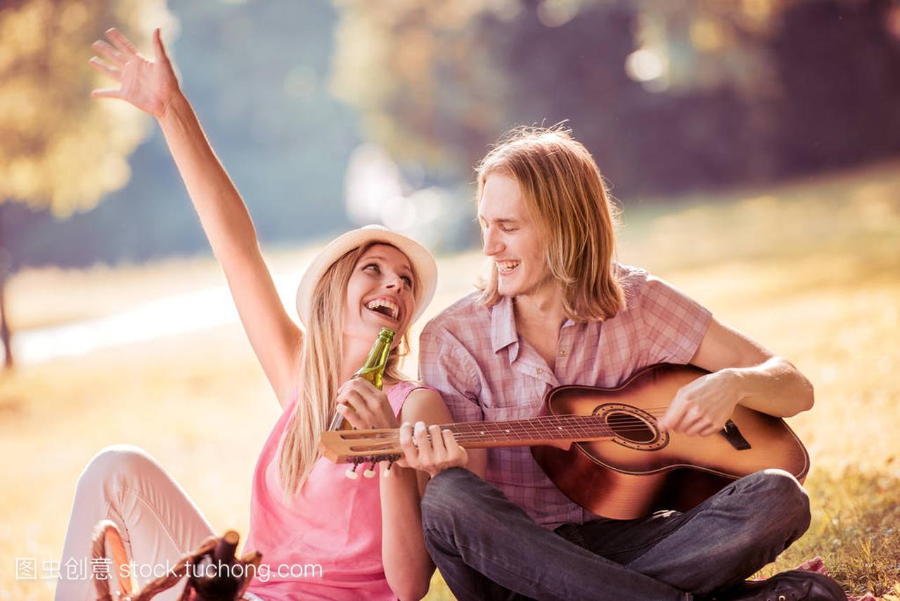 夏天在公园里的年轻人弹吉他给女孩