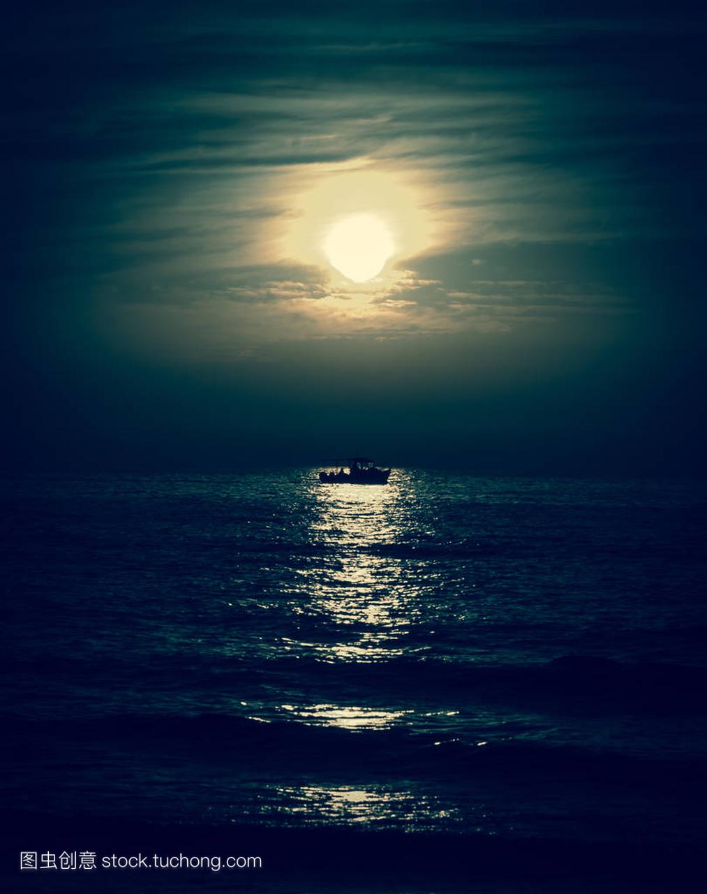 渔民或休闲船向月球航行的剪影。黑暗的天空和