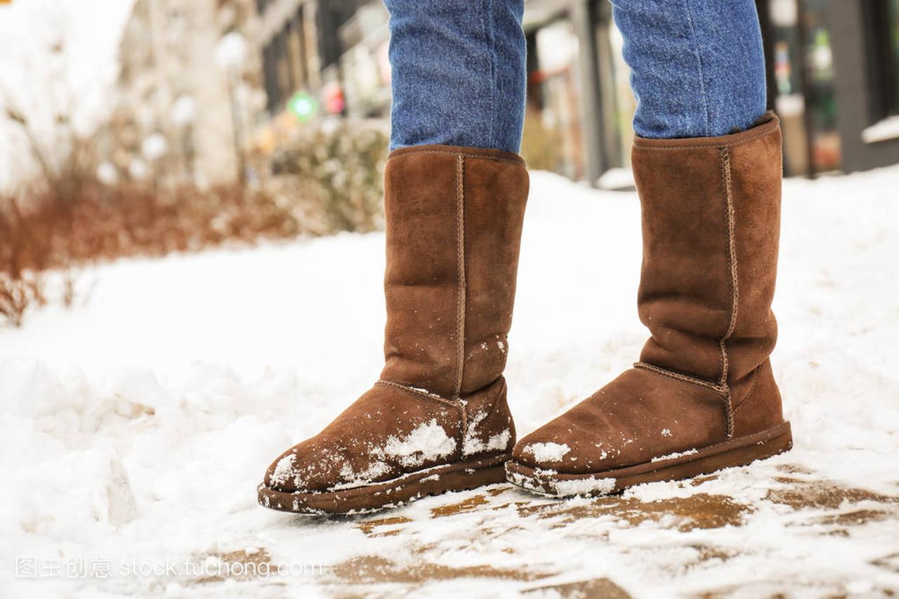 时尚女人冬天穿暖和的鞋子在城市街道上