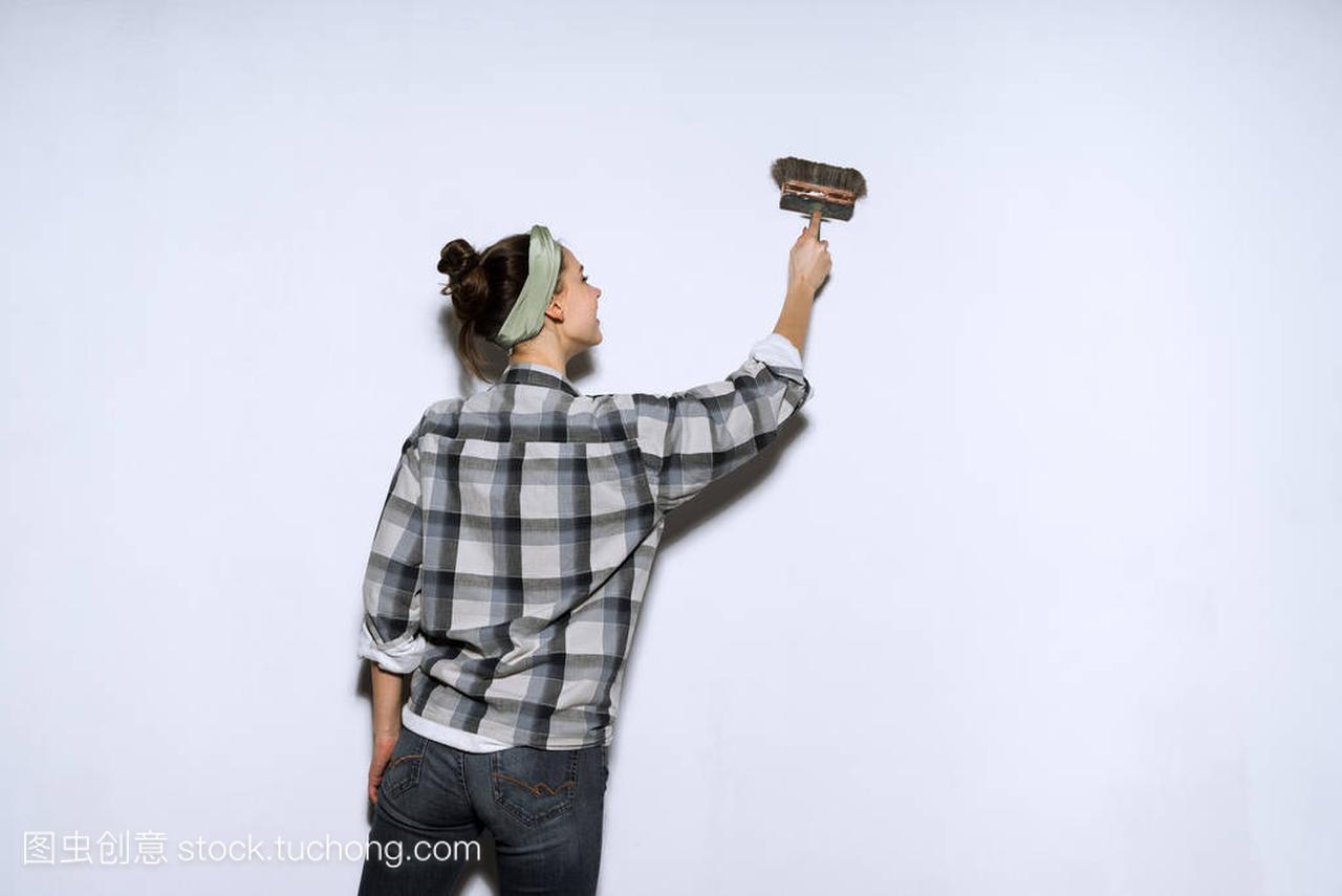 小女孩画家在格子衬衣画墙壁刷子, 修理在一个