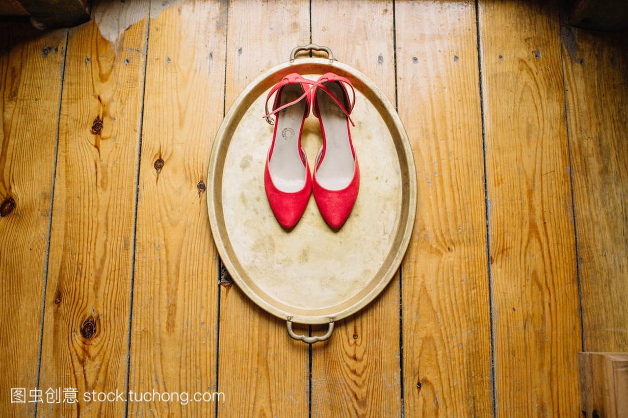 新娘的红高跟鞋在金色托盘上的木地板上。婚礼