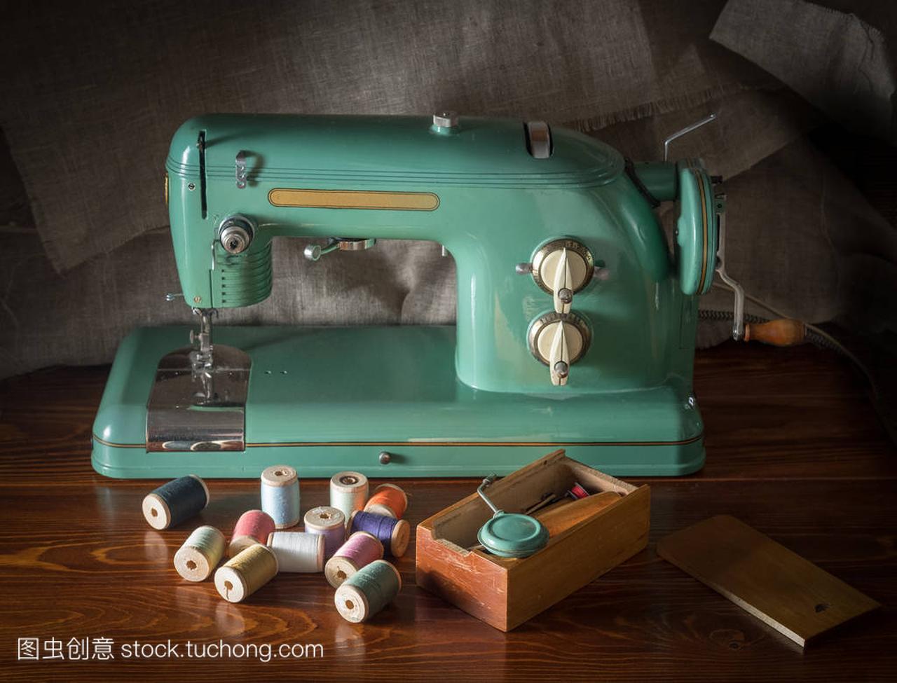 一台旧的电动缝纫机, 带有工具的盒子和洒有螺