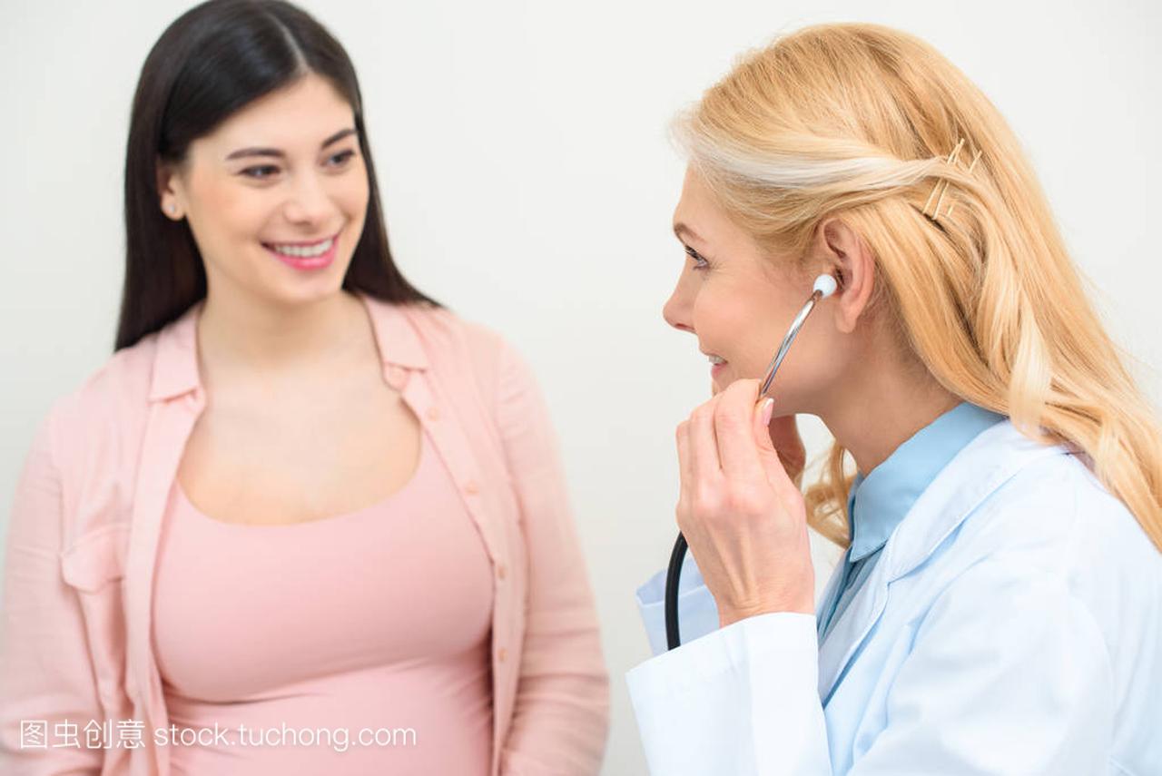 产科妇科医生的特写镜头孕妇用听诊器听胎儿的