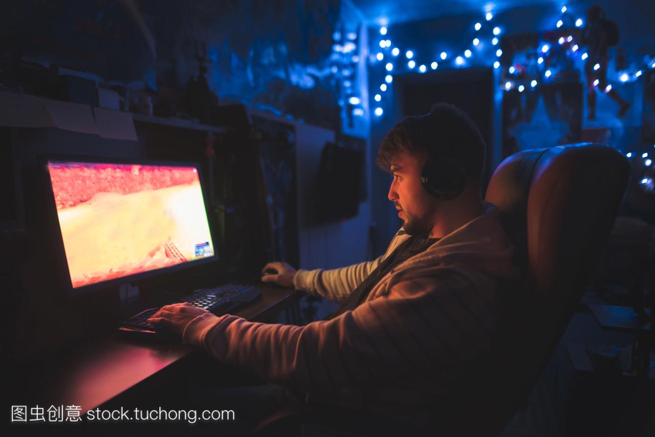 玩家晚上坐在电脑后面的舒适房间里玩游戏。一