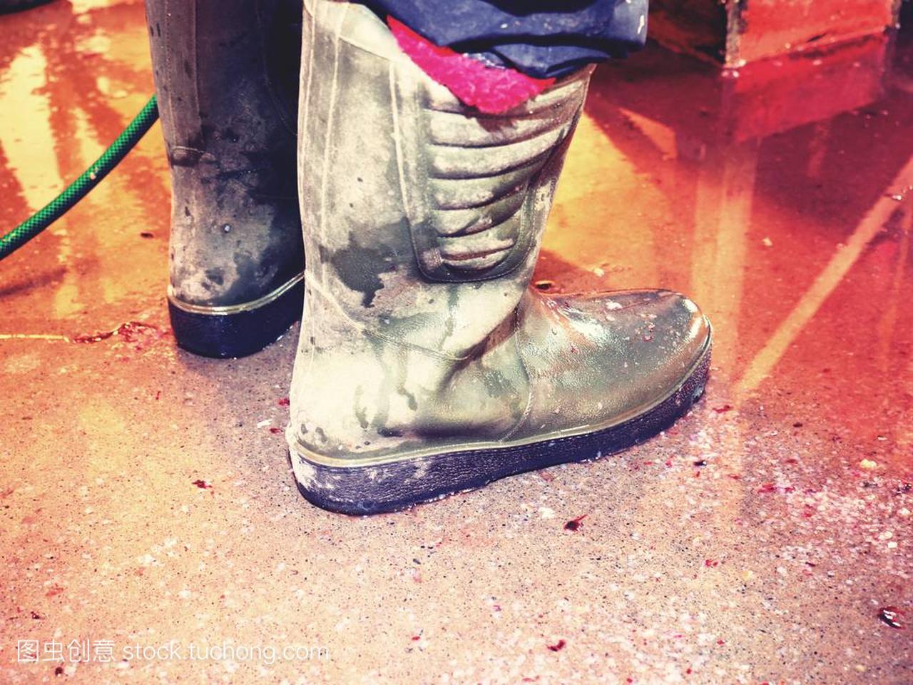 在鱼屠宰厂的高粘胶靴。红血地板波纹管撕裂板