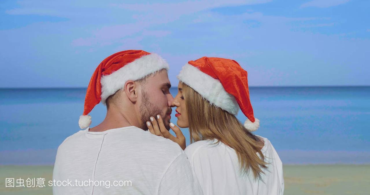 圣诞节美丽的海滩情侣戴着圣诞老人的帽子在夏