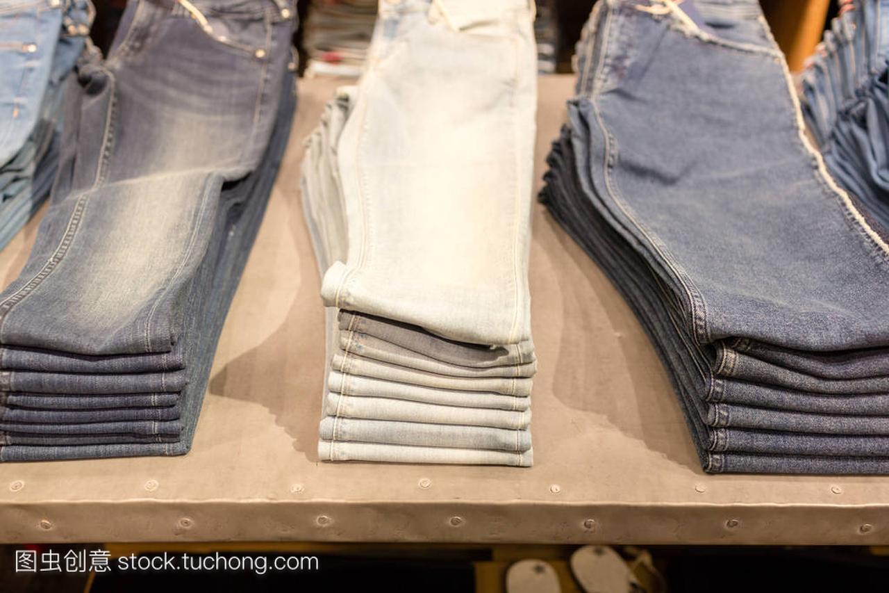 一堆蓝色牛仔裤在商店里。购物销售背景主题。