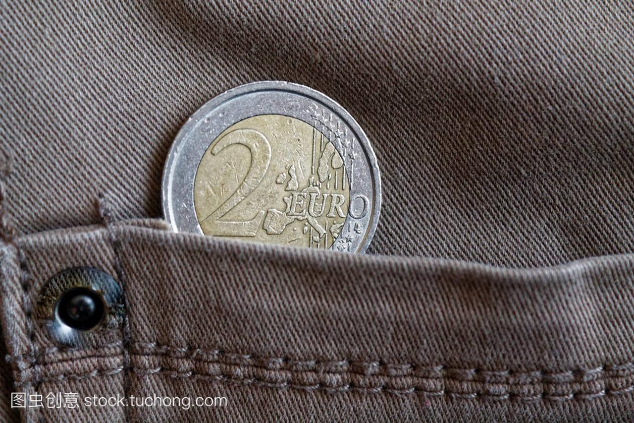 欧元硬币与面值2欧元的口袋里的老式灰色牛仔