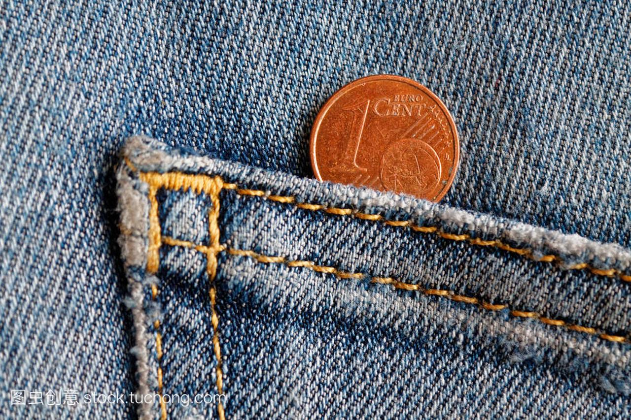 欧元硬币与一欧元面额的旧蓝色牛仔牛仔裤口袋