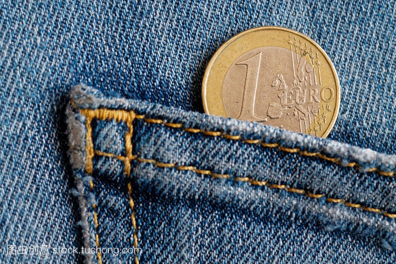 欧元硬币与一欧元面额的蓝色牛仔牛仔裤口袋里