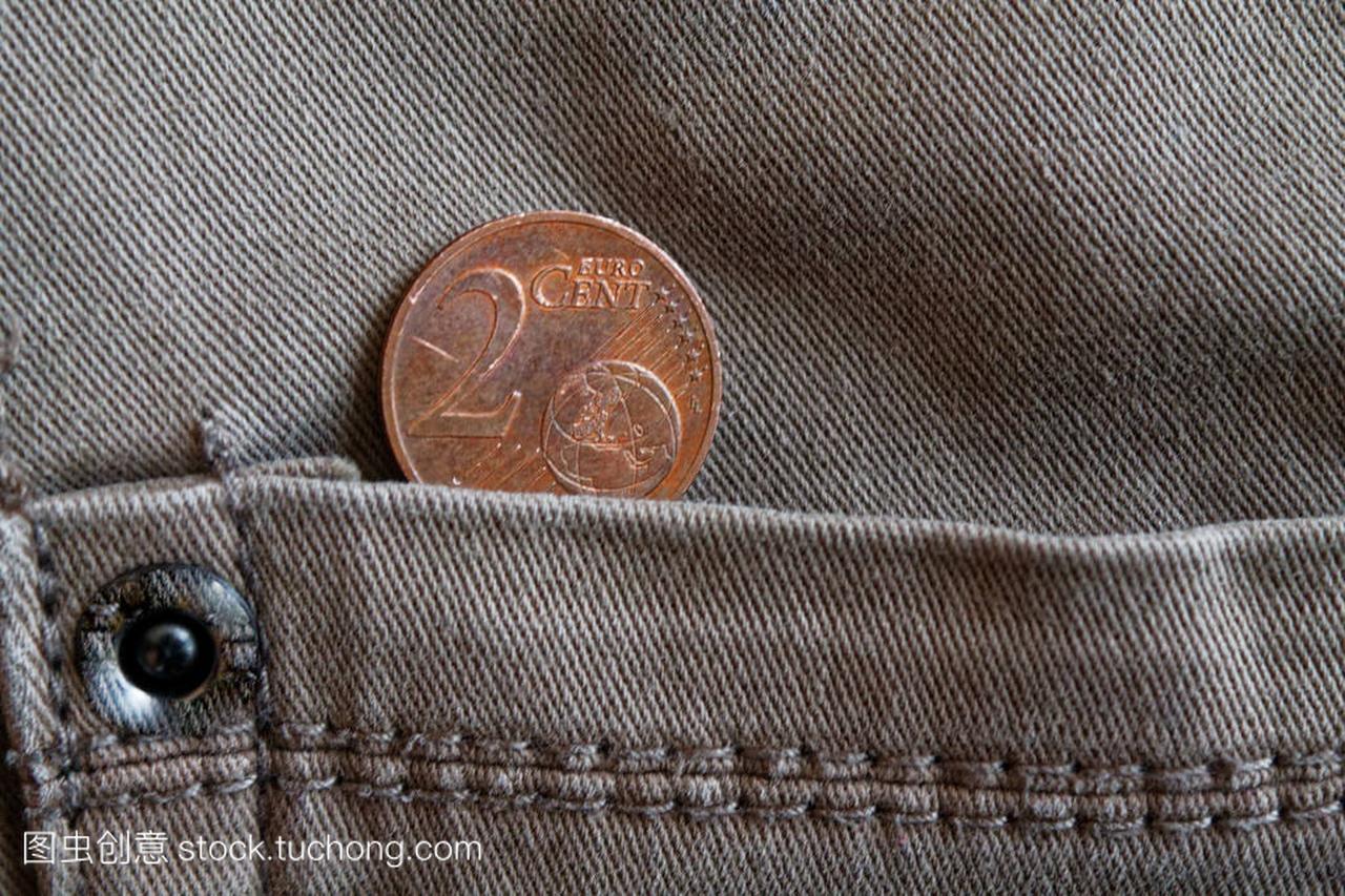欧元硬币的面额2欧元的旧灰色牛仔牛仔裤口袋
