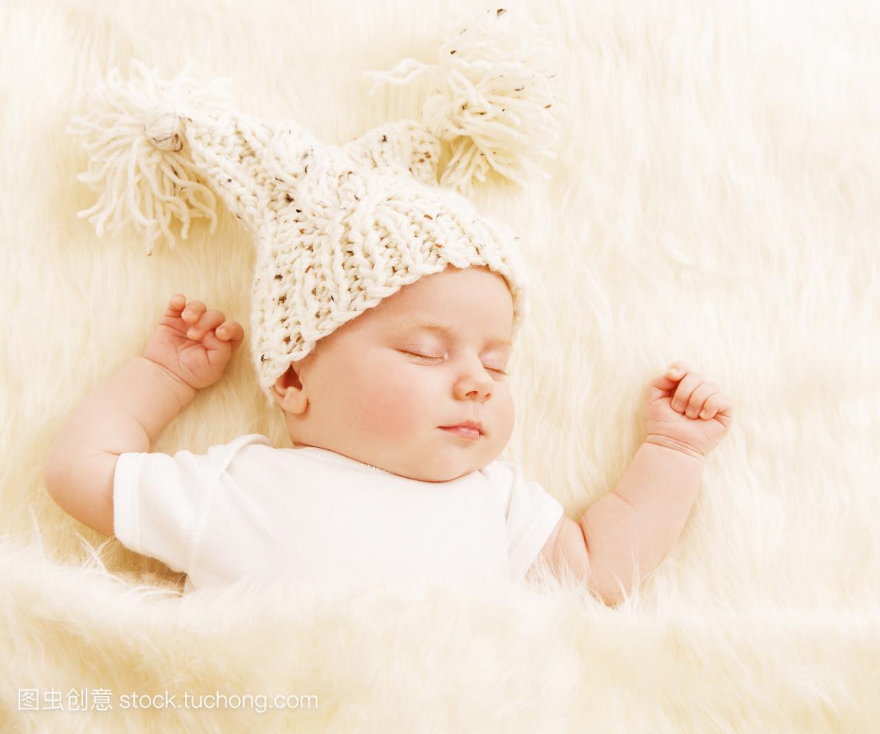 婴儿睡眠, 戴着羊毛帽子的新生孩子在白色毛皮