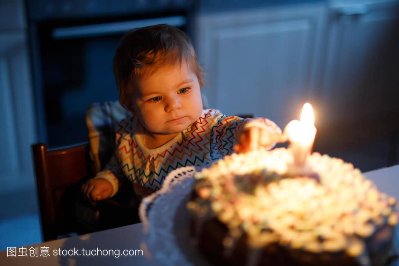 可爱的小女孩庆祝第一个生日。儿童吹一蜡烛自