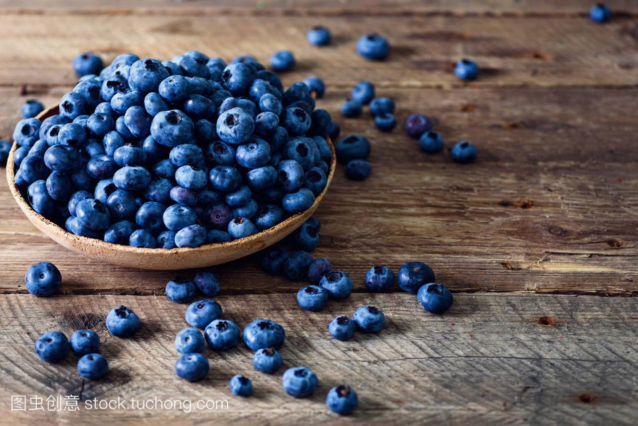 木桌上的蓝莓。与 copyspace 的葡萄酒背景蓝