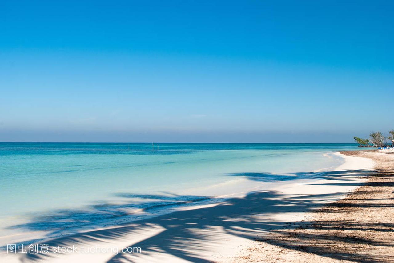在古巴岛 Jutias 海滩上的棕榈影。船和蓝海在
