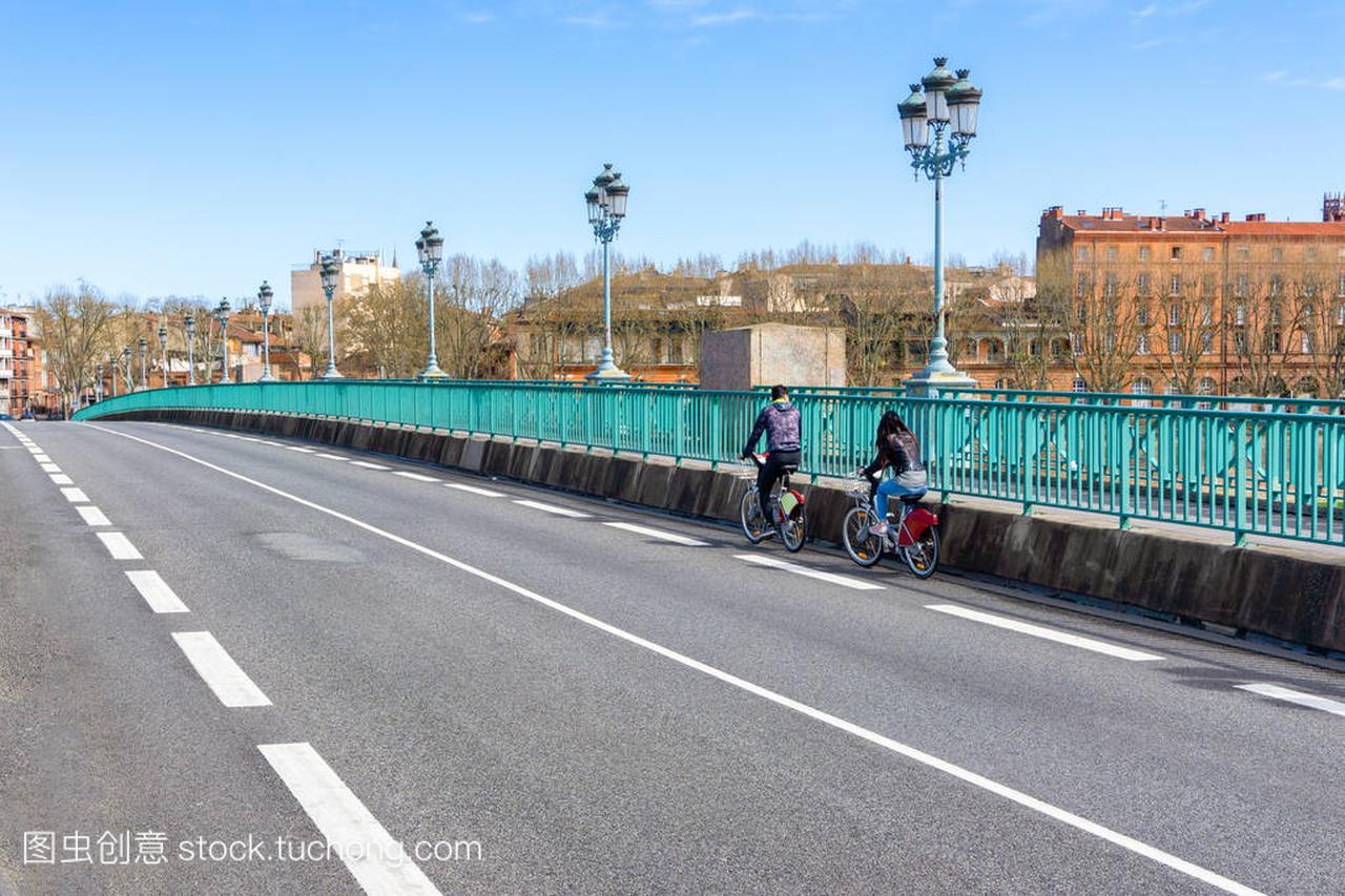 人们骑自行车在自行车车道安全横跨城市桥梁,