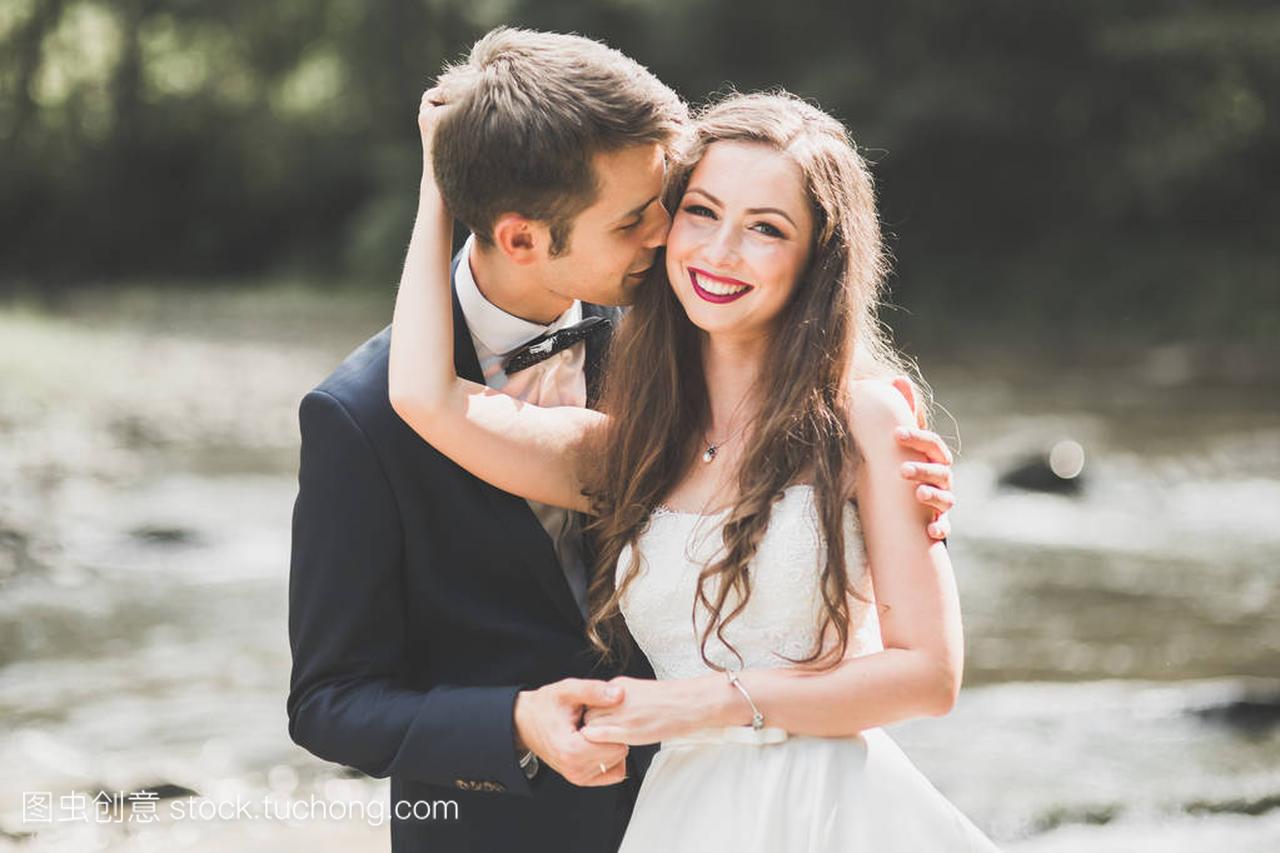 美丽婚礼情侣接吻和拥抱接近岸边的石头山区河