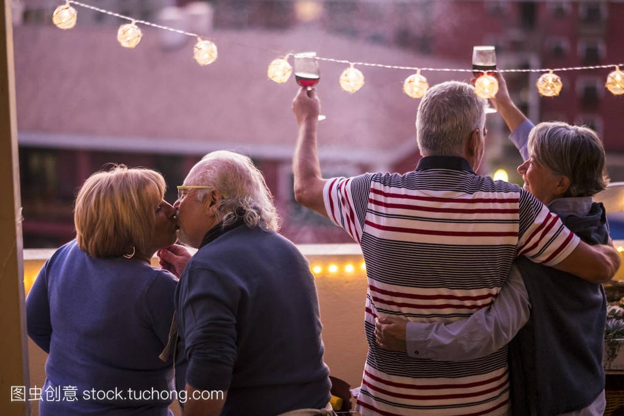 四70岁的老人在阳台上庆祝用玻璃酒杯和红酒
