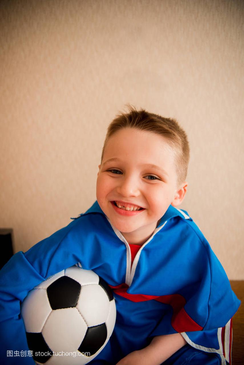 一个穿着蓝色运动制服的足球笑着欢快的男孩。