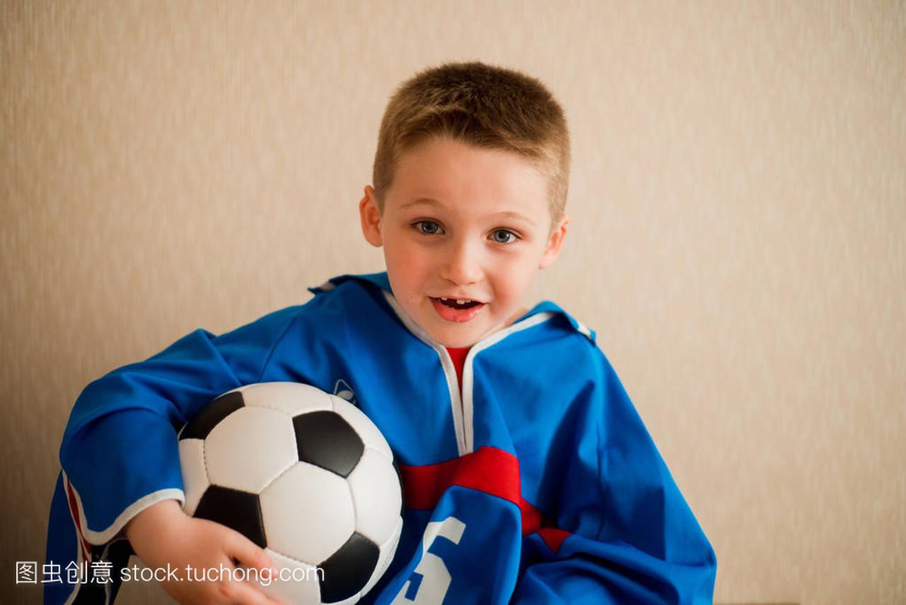 一个穿着蓝色运动制服的足球笑着欢快的男孩。