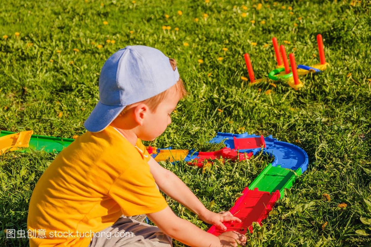 男孩玩玩具车在绿色的草坪上