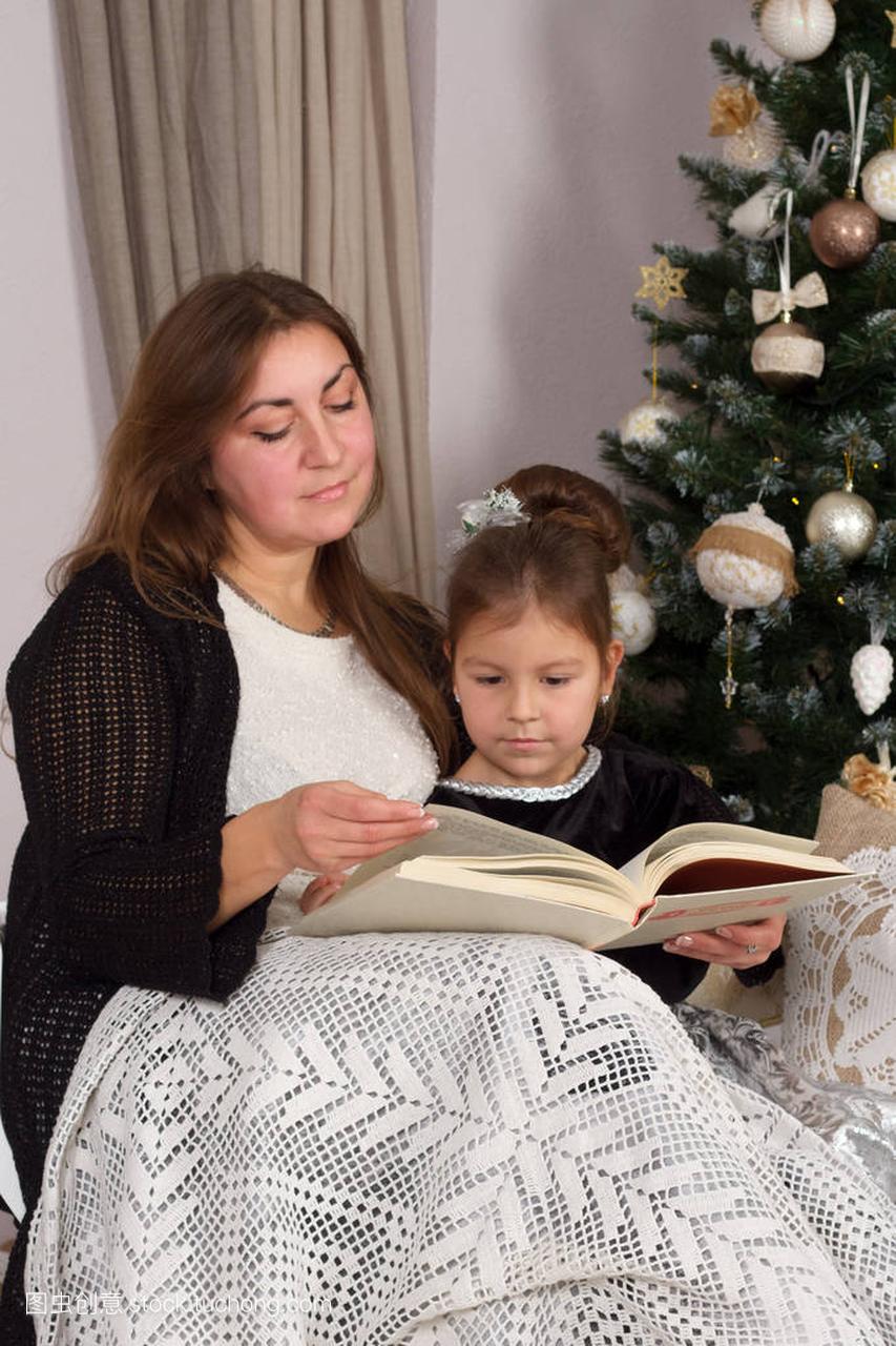 母亲和女儿在圣诞夜读了一本书在壁炉