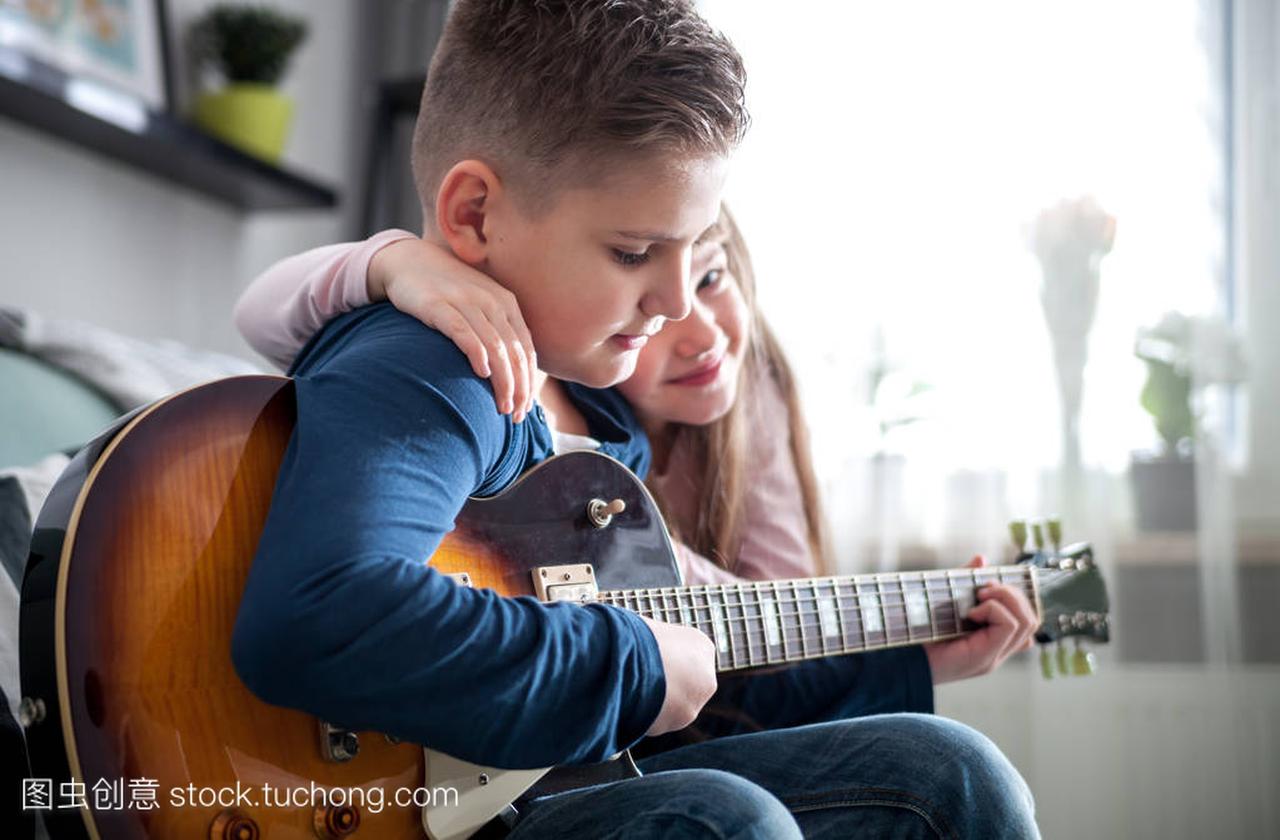 青春期男孩和妹妹在家里玩电吉他