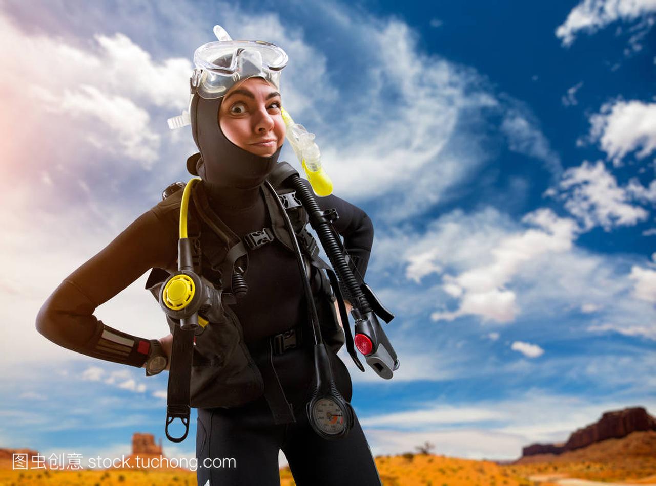 女潜水员在潜水衣和潜水装备在海滩上的姿势。