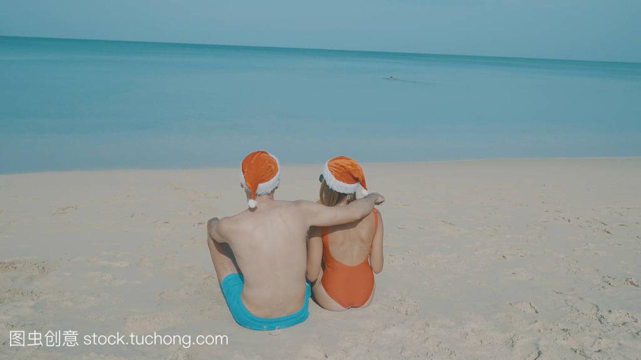 圣诞节美丽的海滩情侣戴着圣诞老人的帽子在夏